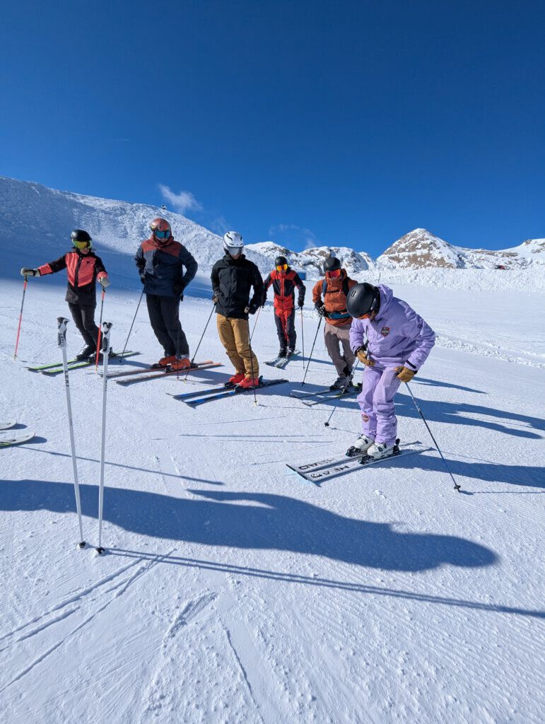 Skilehrer führt kleine Gruppe beim privaten Skiunterricht im verschneiten Skigebiet Kaprun