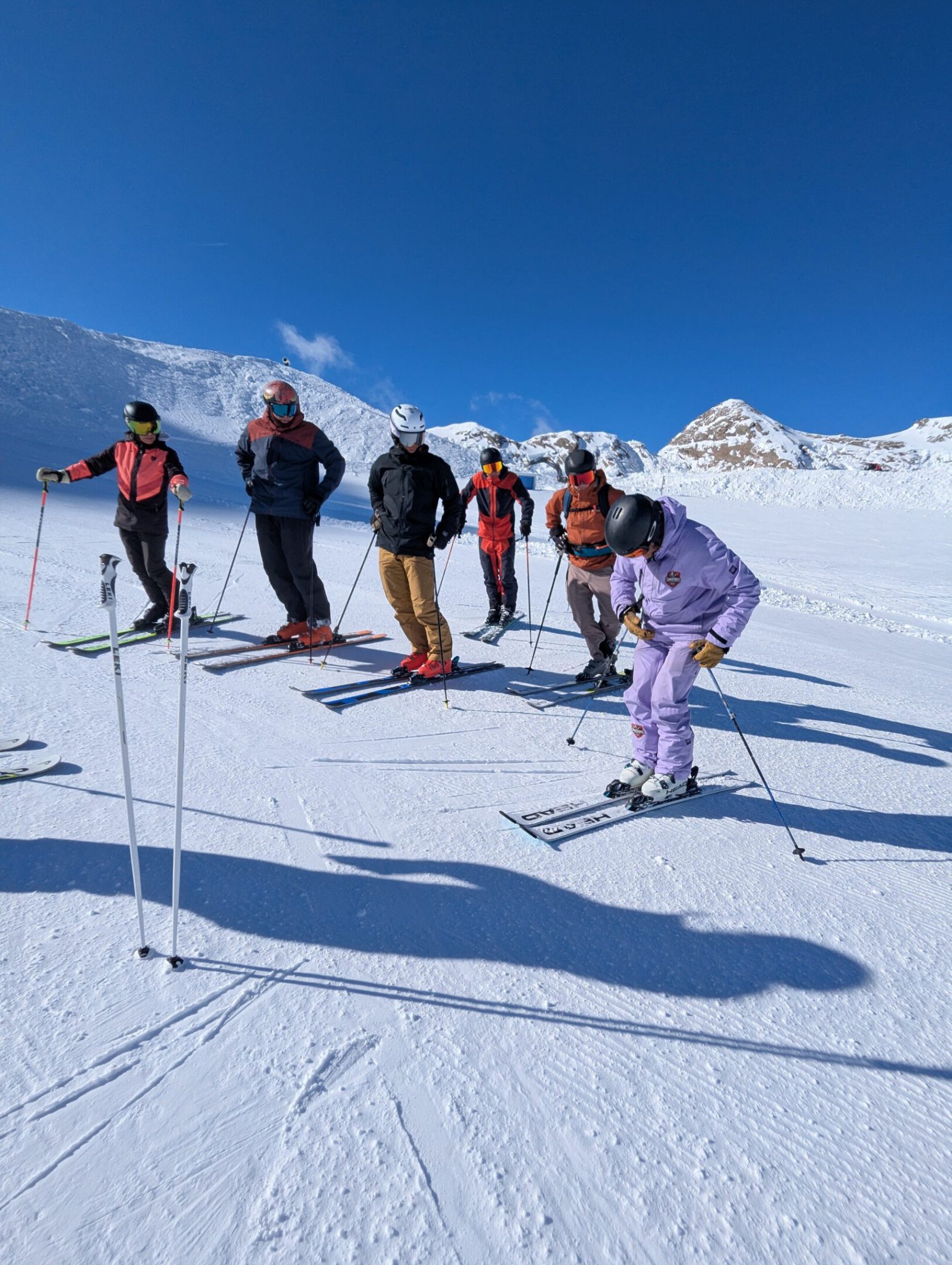 Skilehrer führt kleine Gruppe beim privaten Skiunterricht im verschneiten Skigebiet Kaprun