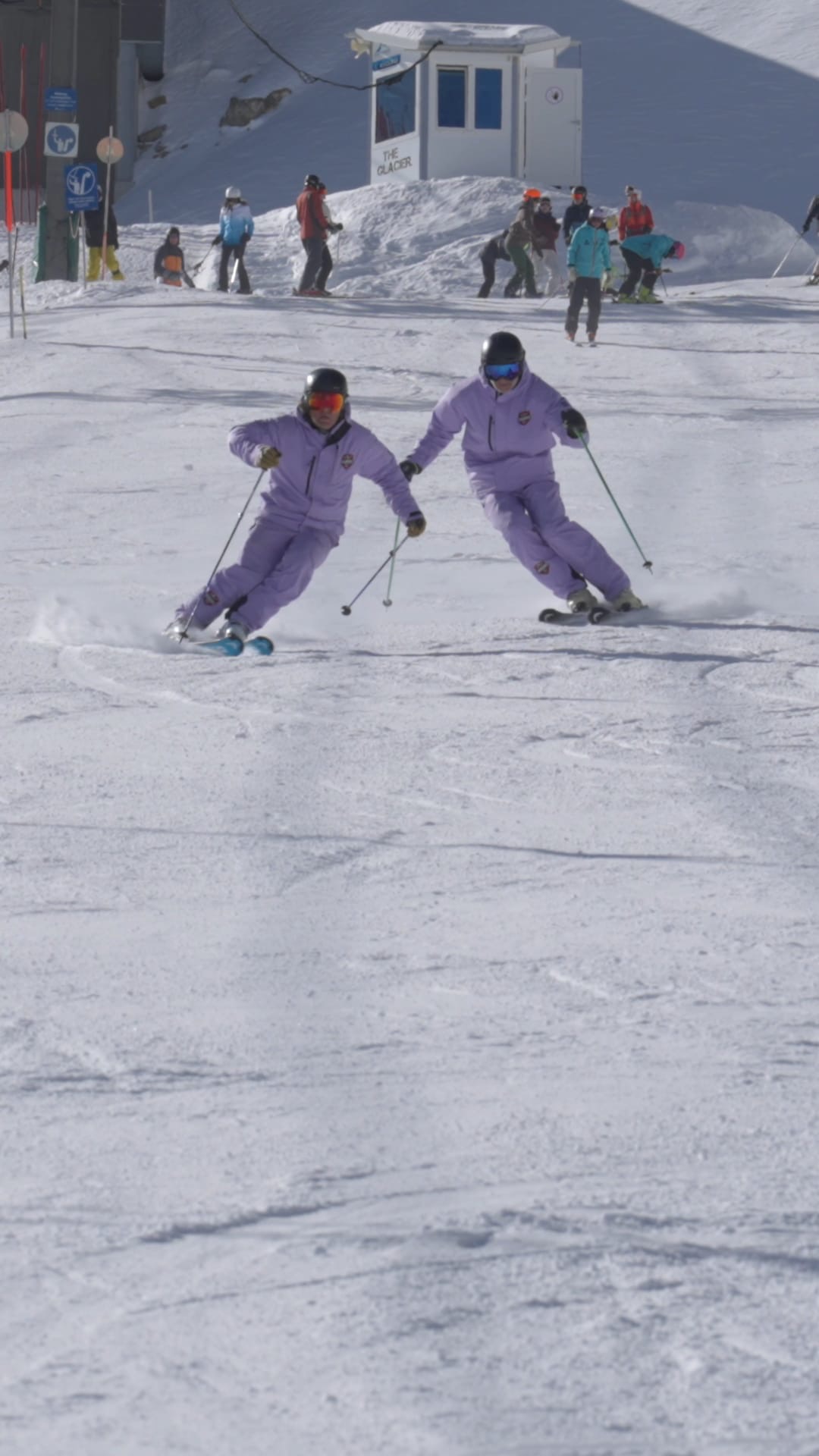 Drei Skilehrer in blauen Jacken unterrichten Kinder beim Skiunterricht im Skigebiet Kaprun